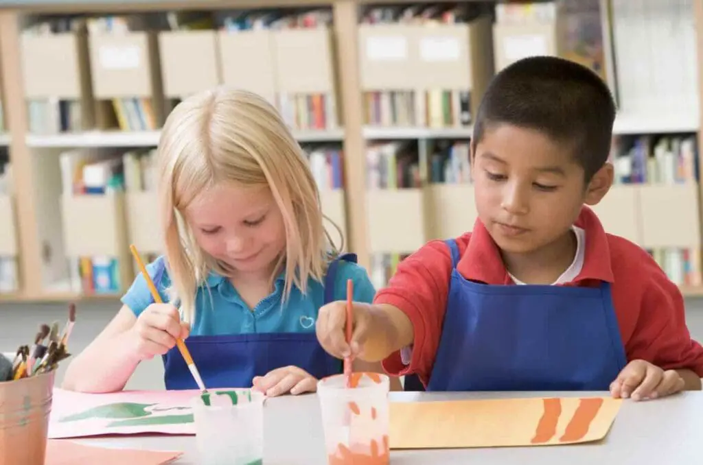 A boy and girl painting on a paper